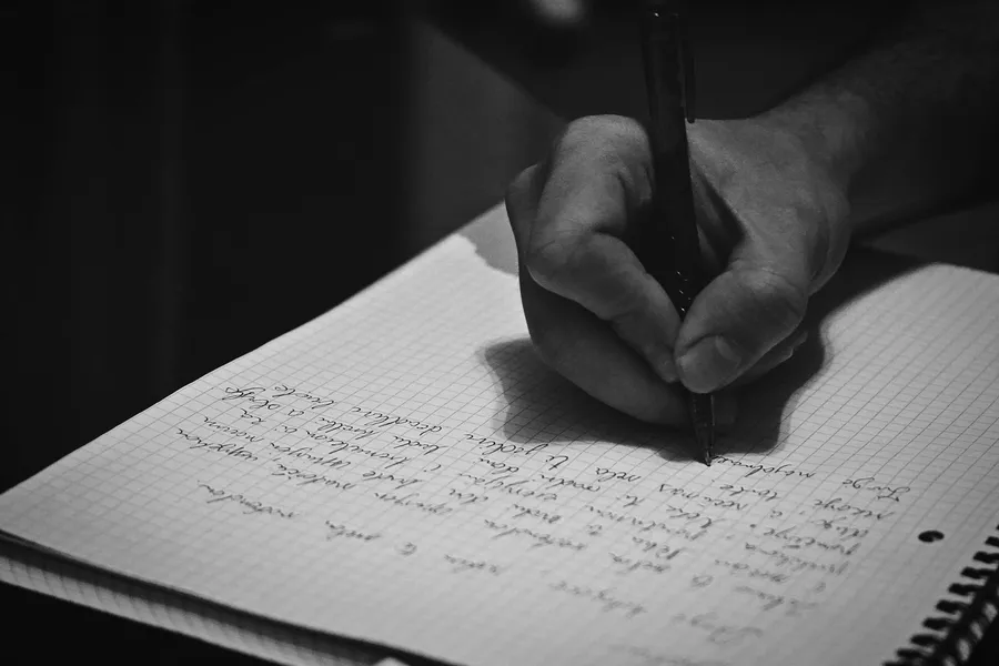 Manos anotando observaciones al margen de un contrato impreso sobre un escritorio.