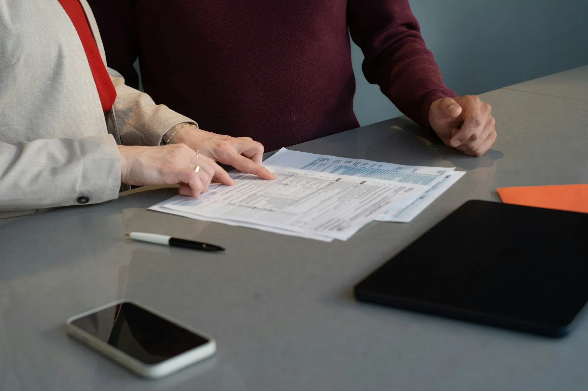 Dos personas revisando documentos sobre una mesa de reuniones.